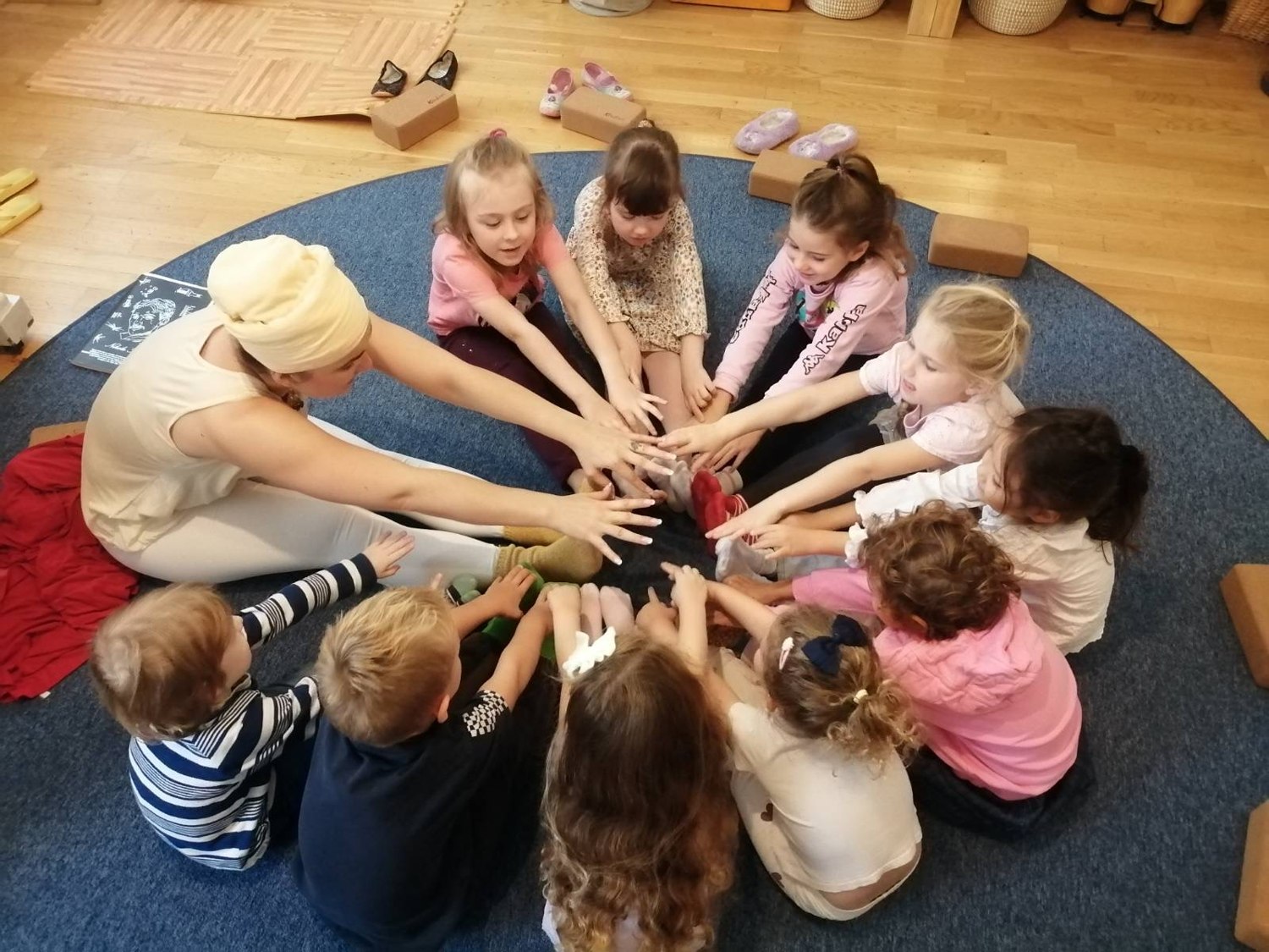 Children and an adult bringing their hands together in a circle