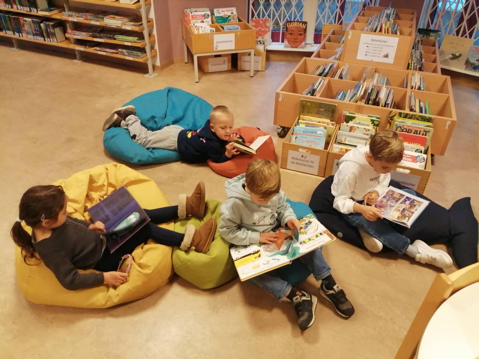 Children looking at books on beanbags in a library