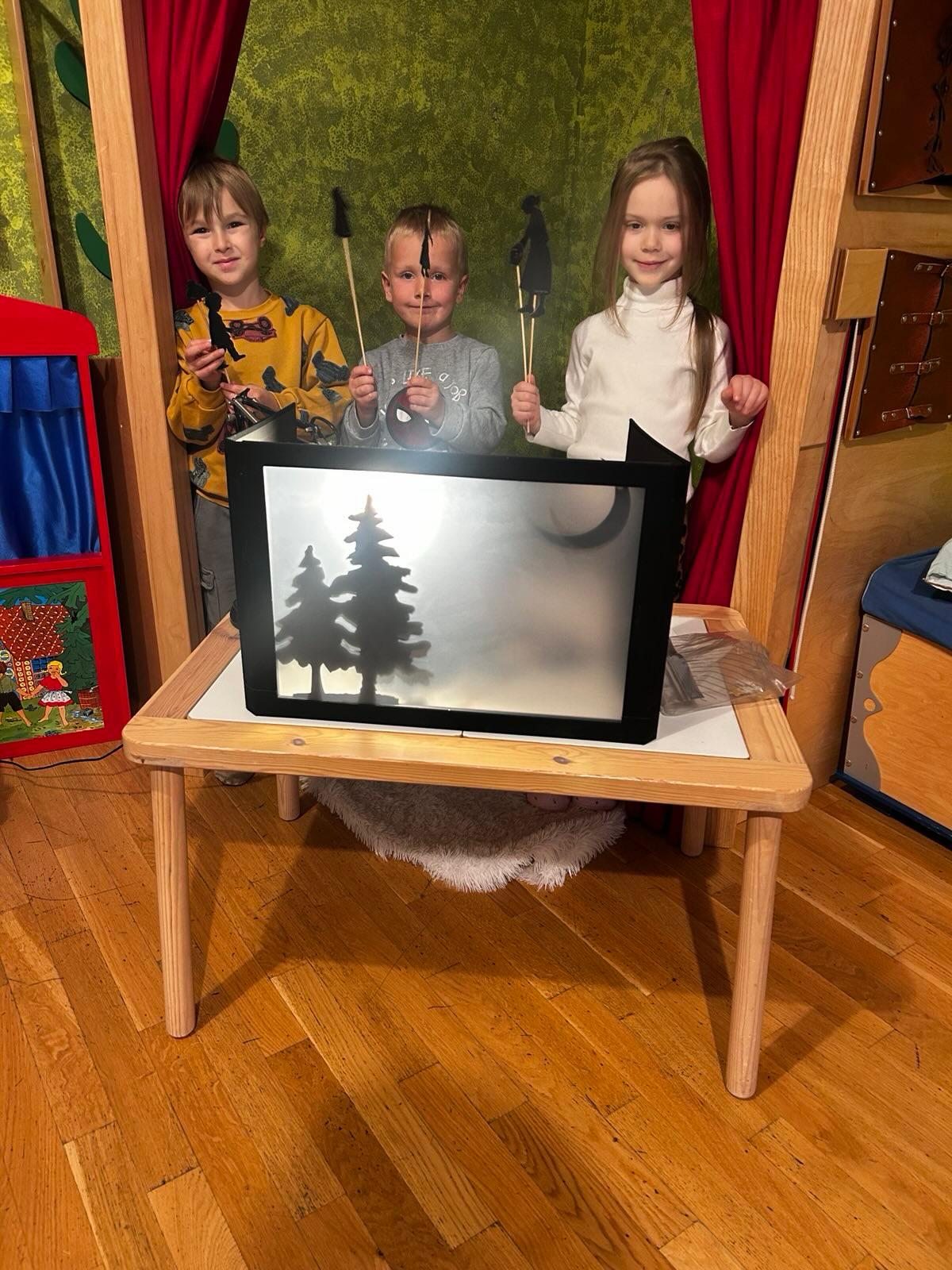 Kinder spielen mit Figuren am Schattentheater
