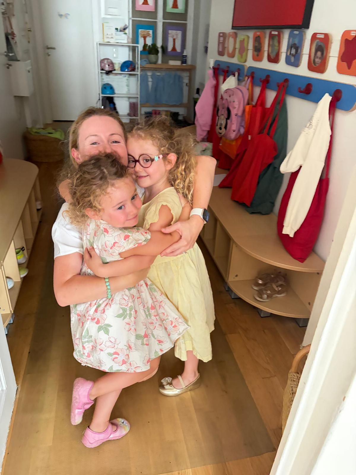 An adult and two children sharing a hug in the cloakroom