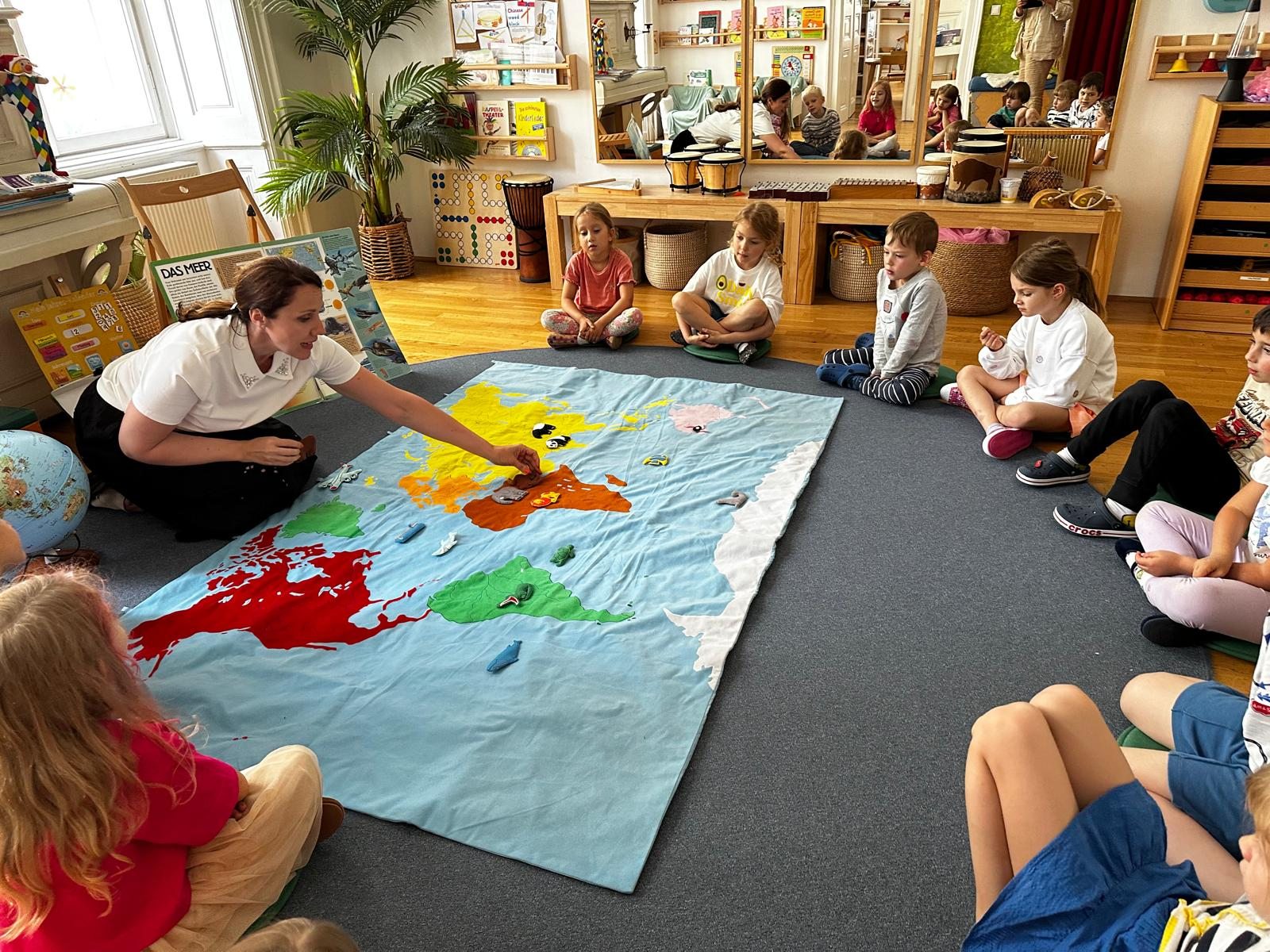Eine Pädagogin und Kinder entdecken gemeinsam eine große Weltkarte